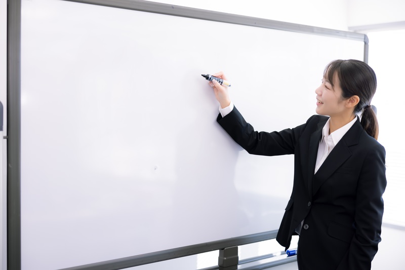 ホワイトボードで授業をする女性講師(写真素材)